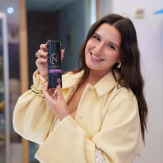 Woman holding a Norvell tanning product in an indoor setting